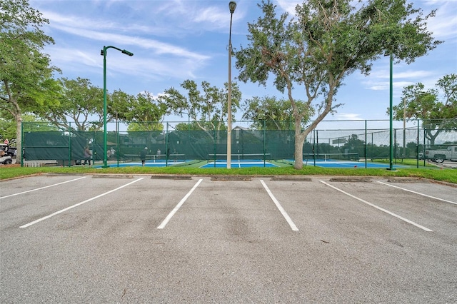 uncovered parking lot with a tennis court and fence