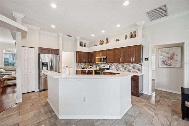 18520 Hidden Pines Way, Hudson, FL 34667 - kitchen with stainless steel appliances, crown molding, light countertops, a kitchen island with sink, and decorative backsplash