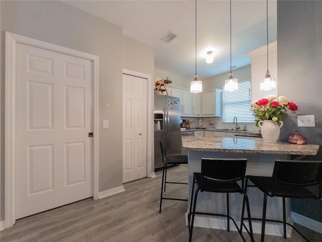 12408 Country White Cir, Tampa, FL 33635 - kitchen with stainless steel fridge with ice dispenser, a peninsula, a sink, white cabinets, and a breakfast bar