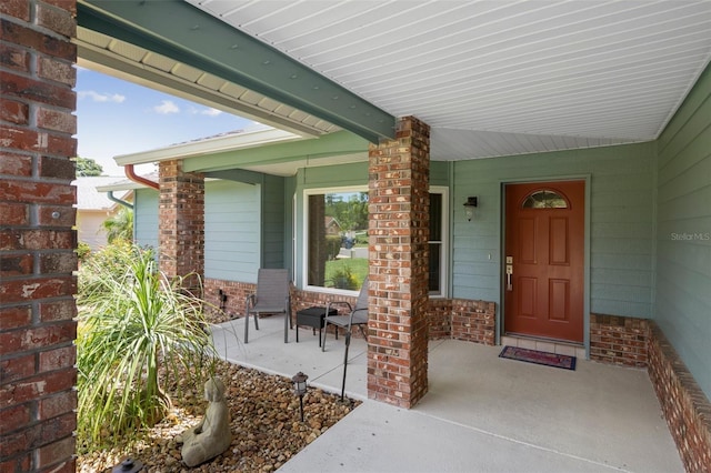 entrance to property with covered porch and brick siding