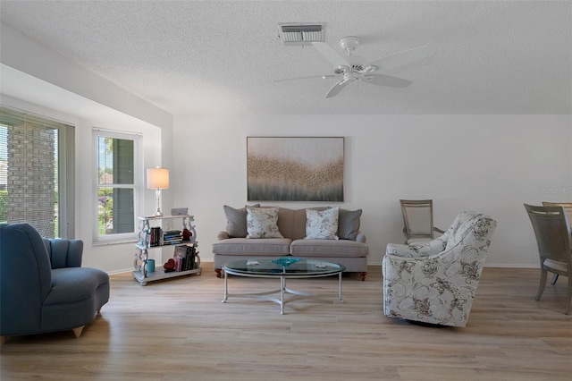 living room featuring wood finished floors, a textured ceiling, a ceiling fan, and baseboards