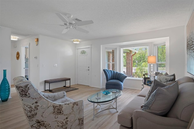 living room featuring a textured ceiling, light wood-style floors, and a ceiling fan
