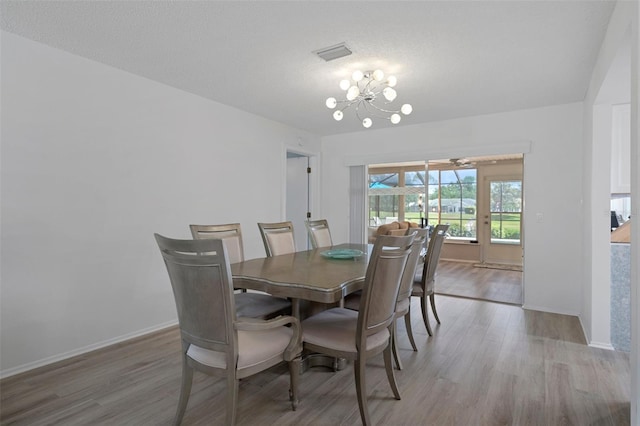 dining space with light wood-style flooring, a chandelier, and baseboards