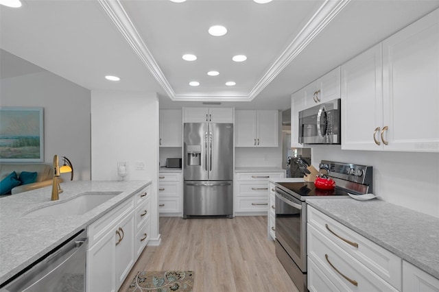 kitchen featuring appliances with stainless steel finishes, a sink, recessed lighting, light wood-style floors, and ornamental molding