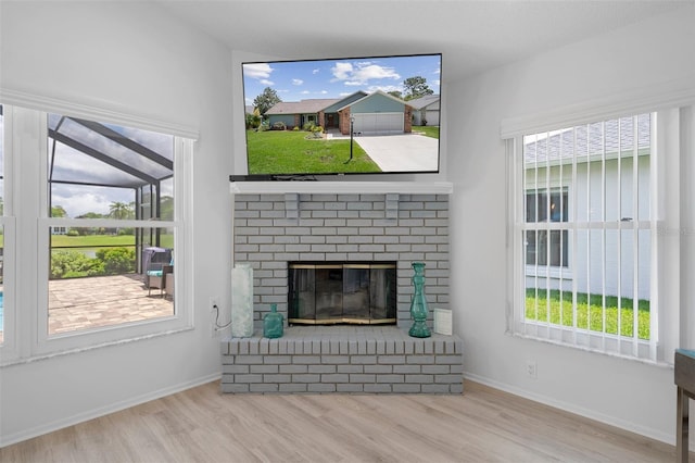 unfurnished living room featuring wood finished floors, a brick fireplace, and baseboards