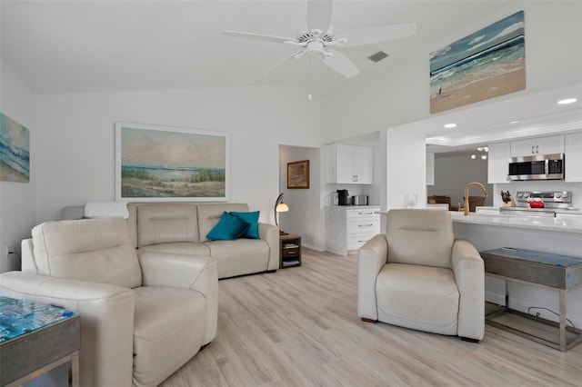 living area featuring vaulted ceiling, ceiling fan, light wood-style floors, and recessed lighting