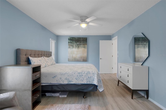 bedroom with light wood-style flooring, ceiling fan, and a textured ceiling