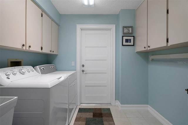 clothes washing area with cabinet space, washer and dryer, baseboards, light tile patterned floors, and a textured ceiling