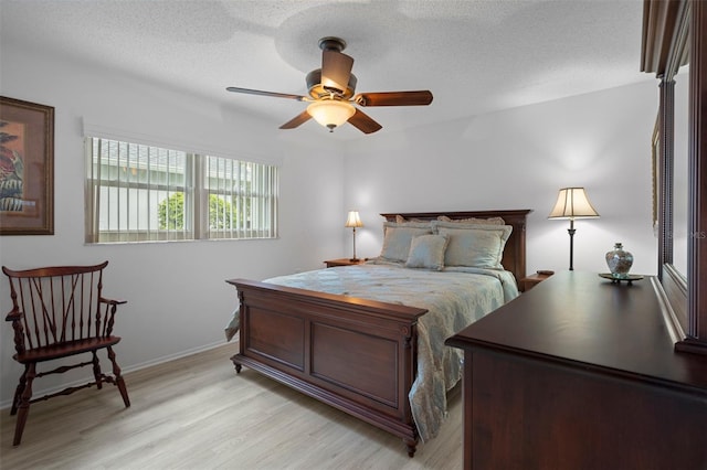 bedroom with light wood-style floors, baseboards, a textured ceiling, and ceiling fan