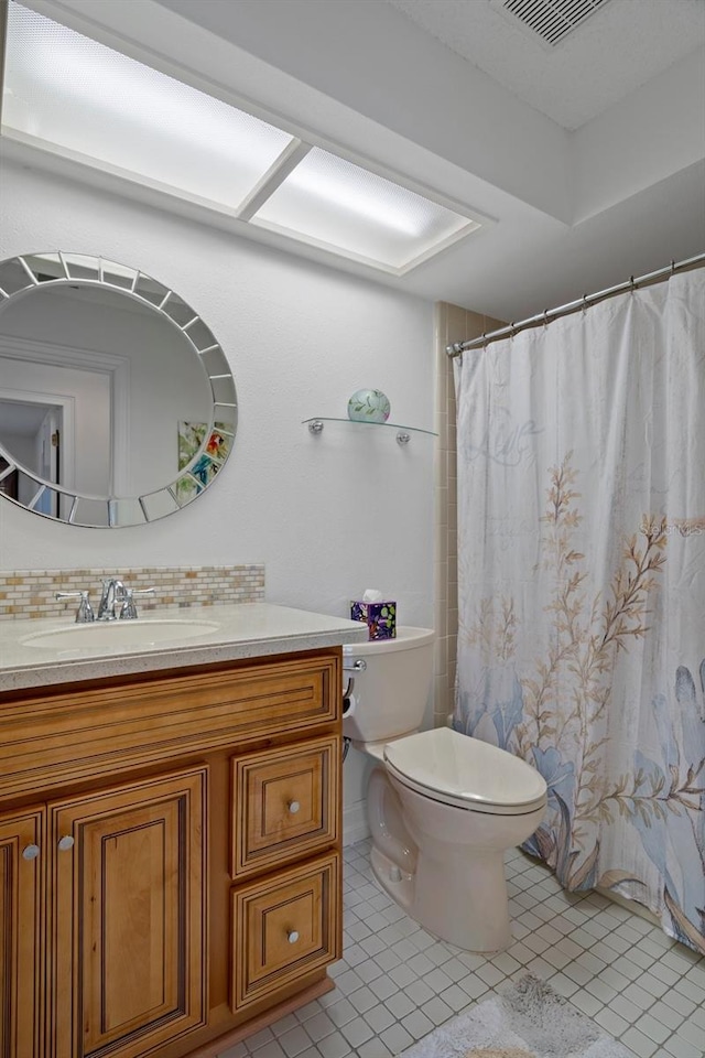 full bathroom featuring toilet, tile patterned floors, vanity, and tasteful backsplash
