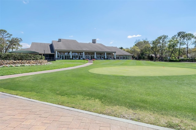 surrounding community featuring an area to practice putting, a lawn, and golf course view