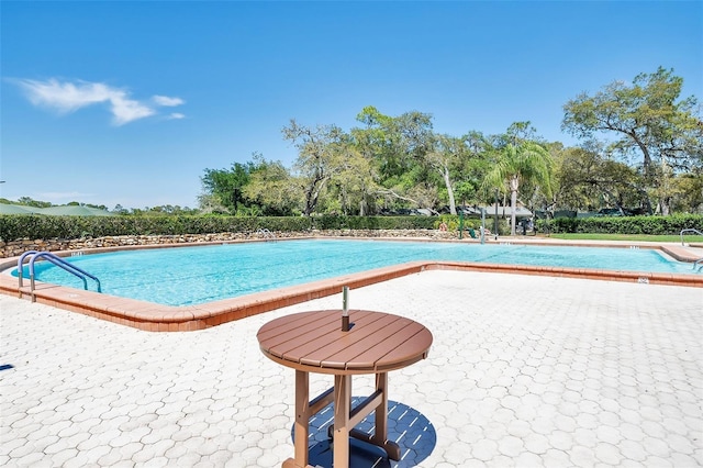 community pool with view of scattered trees and a patio