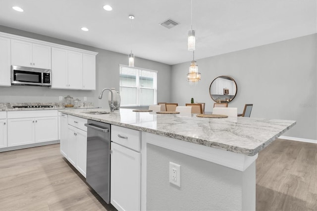 12854 Rangeland Blvd, Odessa, FL 33556 - kitchen with stainless steel appliances, light wood-style floors, recessed lighting, a center island with sink, and white cabinets