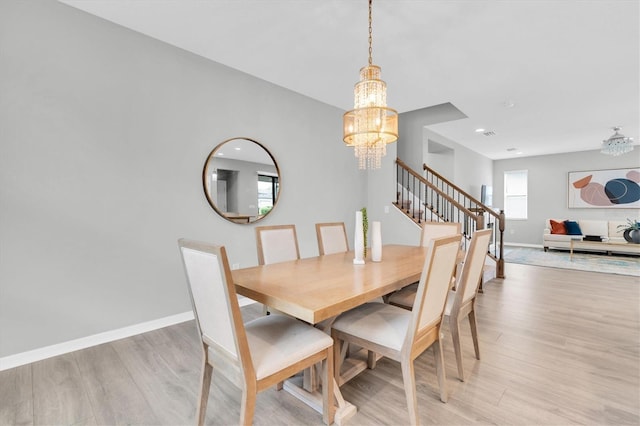 12854 Rangeland Blvd, Odessa, FL 33556 - dining space featuring a chandelier, baseboards, light wood-style flooring, and stairs