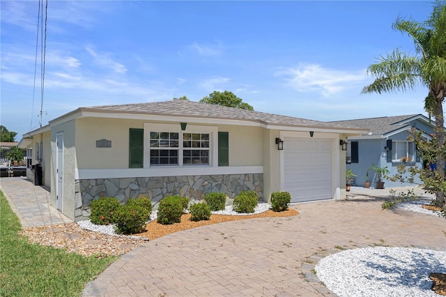 5045 Pelican Dr, New Port Richey, FL 34652 - view of front of home with an attached garage, stucco siding, stone siding, and decorative driveway