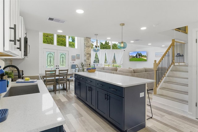 7422 New York Ave, Hudson, FL 34667 - kitchen with a sink, light wood-style flooring, white cabinetry, a kitchen island, and recessed lighting