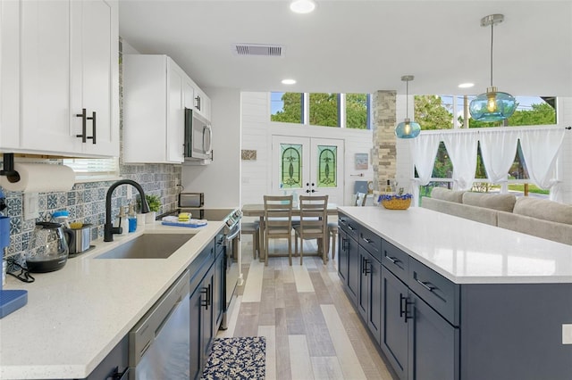 7422 New York Ave, Hudson, FL 34667 - kitchen featuring stainless steel appliances, a sink, white cabinetry, light wood finished floors, and tasteful backsplash