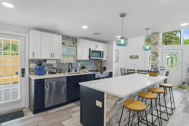 7422 New York Ave, Hudson, FL 34667 - kitchen featuring stainless steel appliances, a sink, a kitchen bar, tasteful backsplash, and light countertops