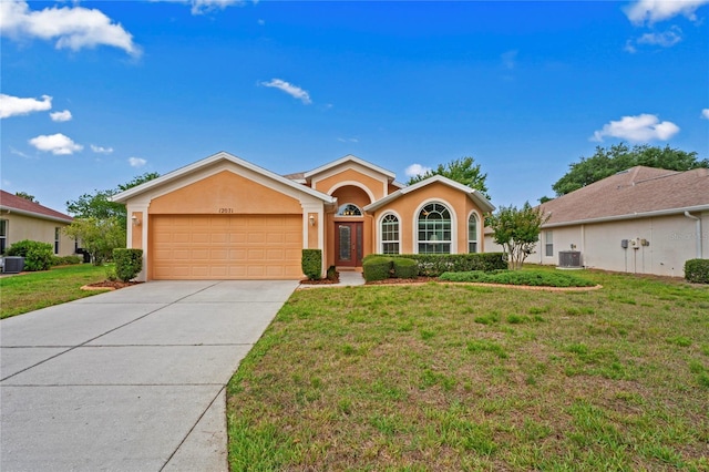 12071 Wexford Blvd, Spring Hill, FL 34609 - view of front of home featuring a garage, stucco siding, central AC unit, driveway, and a front yard