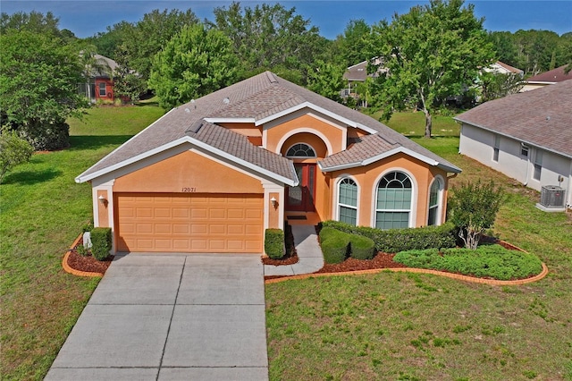 12071 Wexford Blvd, Spring Hill, FL 34609 - view of front of home with central AC, concrete driveway, a front yard, an attached garage, and stucco siding