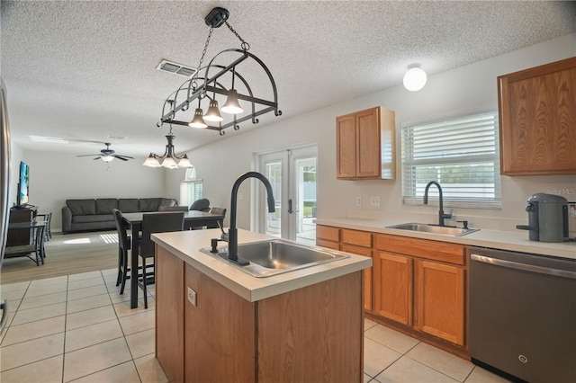 kitchen with dishwasher, a sink, light tile patterned floors, and a textured ceiling