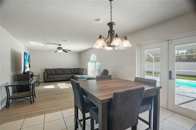 dining space featuring light tile patterned flooring, plenty of natural light, a chandelier, a textured ceiling, and a ceiling fan