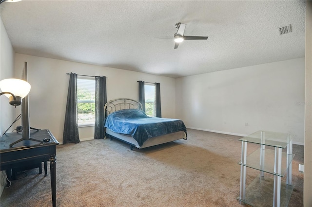 carpeted bedroom with a textured ceiling, baseboards, and ceiling fan