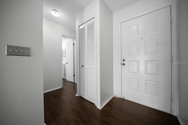 corridor featuring dark wood-style floors, a textured ceiling, and baseboards