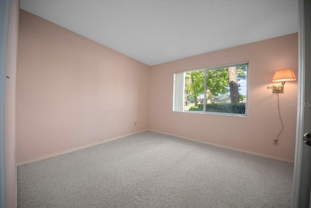 spare room featuring carpet, baseboards, and lofted ceiling
