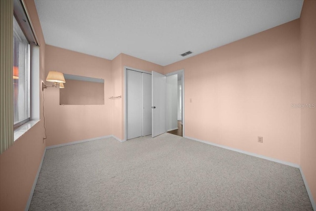 unfurnished bedroom featuring carpet, baseboards, and multiple windows