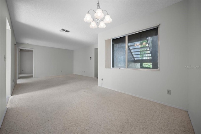 unfurnished room featuring carpet flooring, a chandelier, a textured ceiling, and baseboards