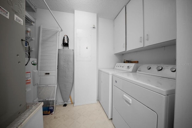 washroom with cabinet space, washer and clothes dryer, light floors, a textured ceiling, and heating unit