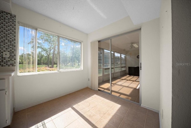 unfurnished sunroom with a textured ceiling and tile patterned floors