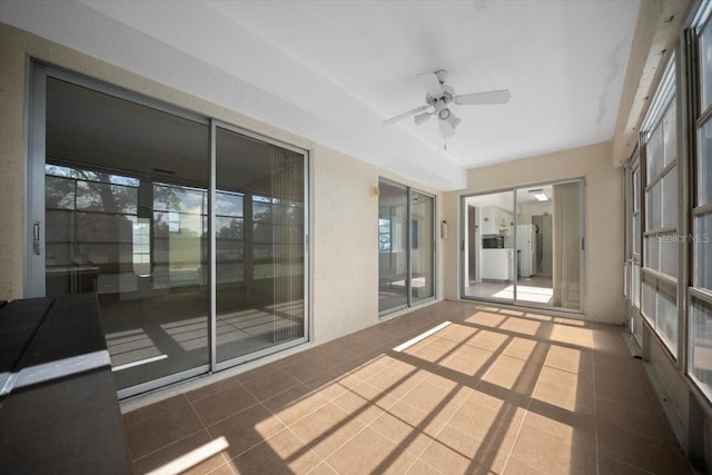 unfurnished sunroom with ceiling fan