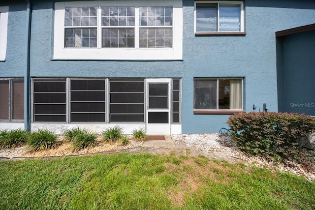 rear view of property featuring stucco siding and a yard