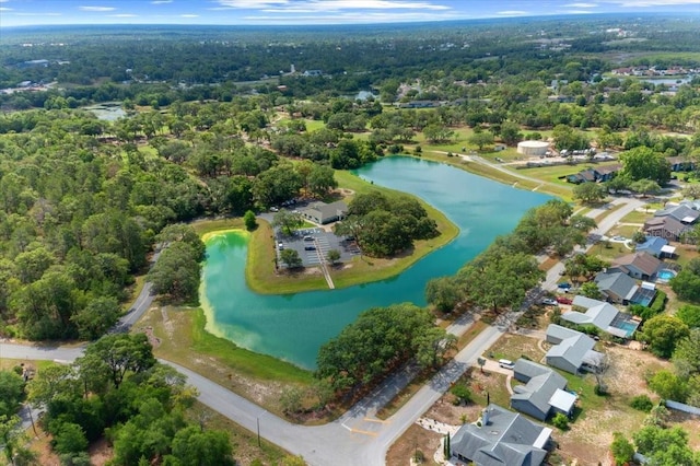 view of property location with a nearby body of water, a heavily wooded area, and nearby suburban area