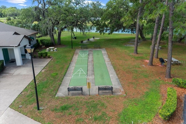 view of community with shuffleboard and a yard