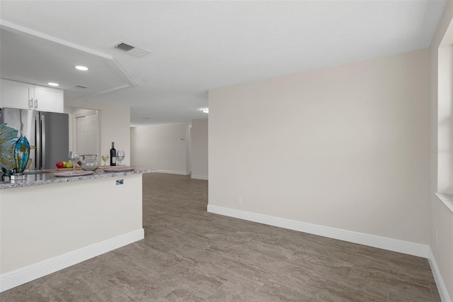 4937 Dory Dr, New Port Richey, FL 34652 - kitchen featuring freestanding refrigerator, light stone countertops, white cabinets, recessed lighting, and baseboards