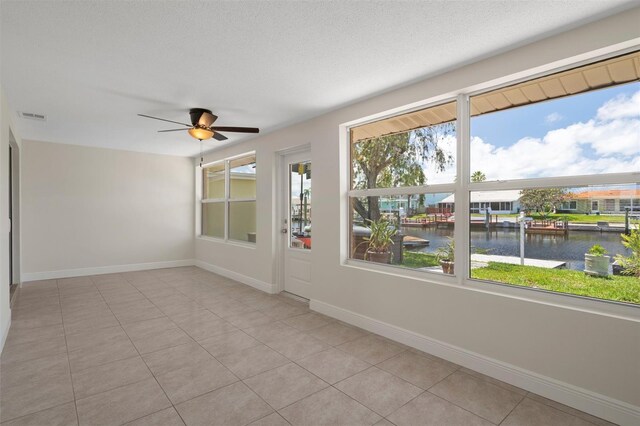 4937 Dory Dr, New Port Richey, FL 34652 - empty room with a water view, a ceiling fan, light tile patterned floors, and baseboards