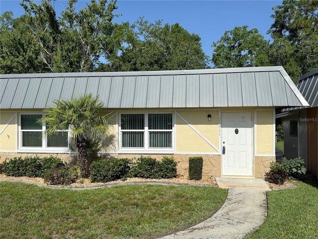 11911 Bayonet Ln, New Port Richey, FL 34654 - view of front of property with stucco siding, a front lawn, and metal roof
