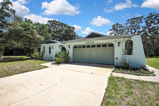 view of front of home featuring stucco siding, a garage, concrete driveway, and a front lawn