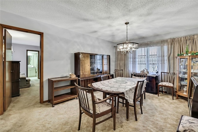 dining space with light colored carpet, a chandelier, and a textured ceiling