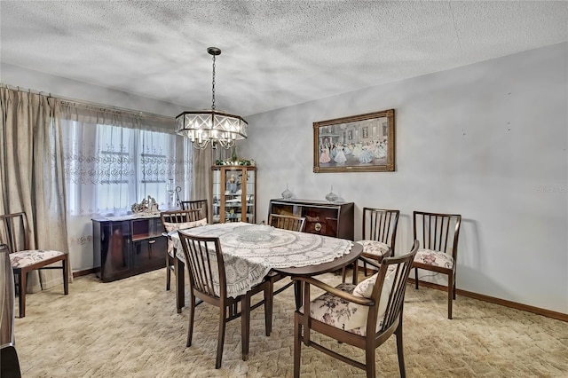 dining space with a chandelier, a textured ceiling, light carpet, and baseboards