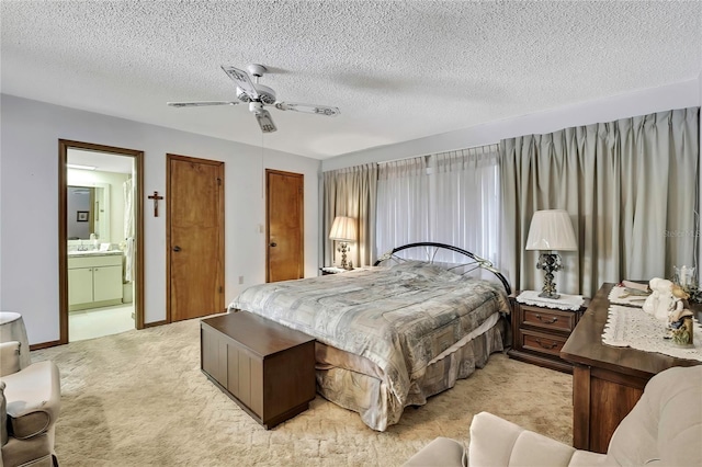 bedroom featuring light colored carpet, ensuite bath, a textured ceiling, a ceiling fan, and two closets