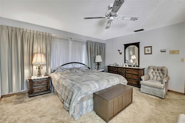 bedroom featuring light carpet, a textured ceiling, and a ceiling fan