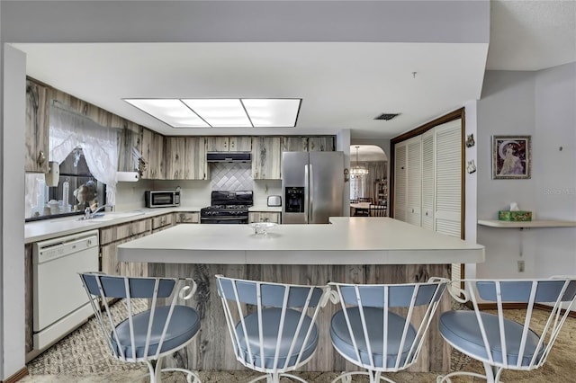 kitchen featuring stainless steel fridge, white dishwasher, gas stove, and light countertops
