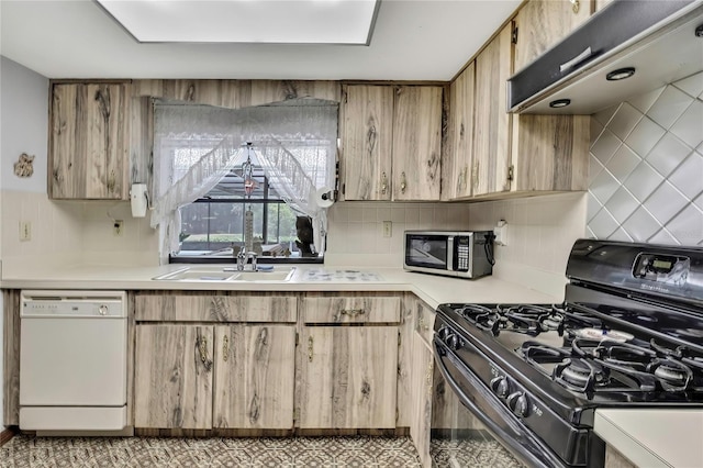 kitchen featuring black gas range oven, white dishwasher, stainless steel microwave, a sink, and light countertops