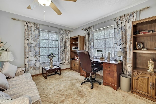 office space with healthy amount of natural light, light carpet, and a ceiling fan