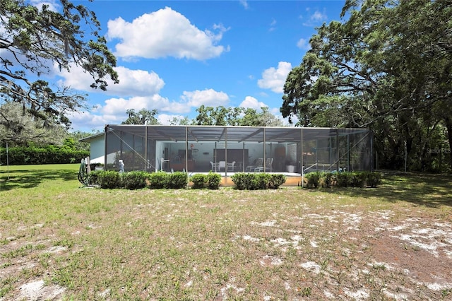 back of property with a yard and glass enclosure