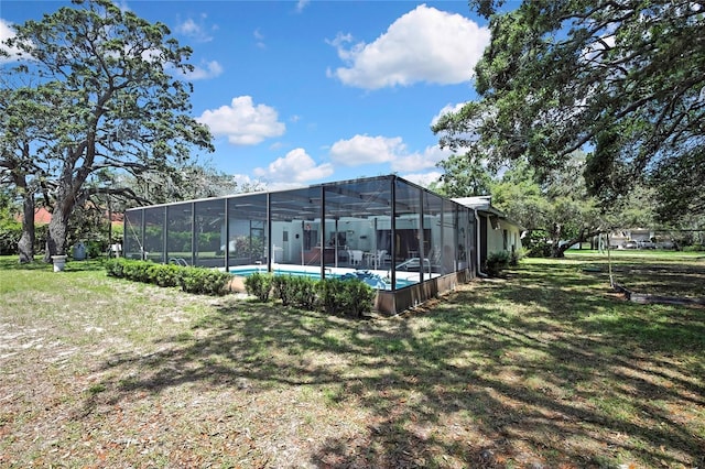 rear view of property featuring a yard, a lanai, and an outdoor pool